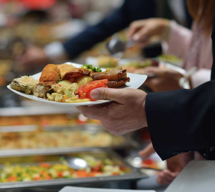 person in suit holding plate of food in office building